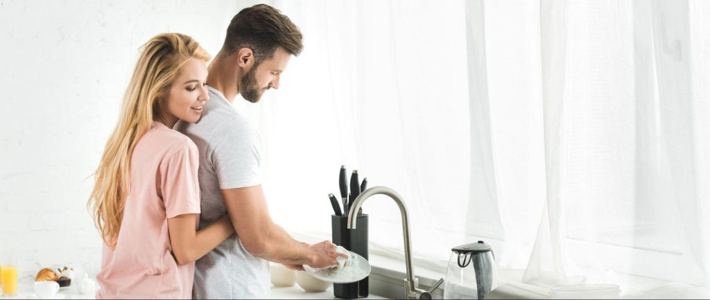 キッチンで食器を洗うカップル