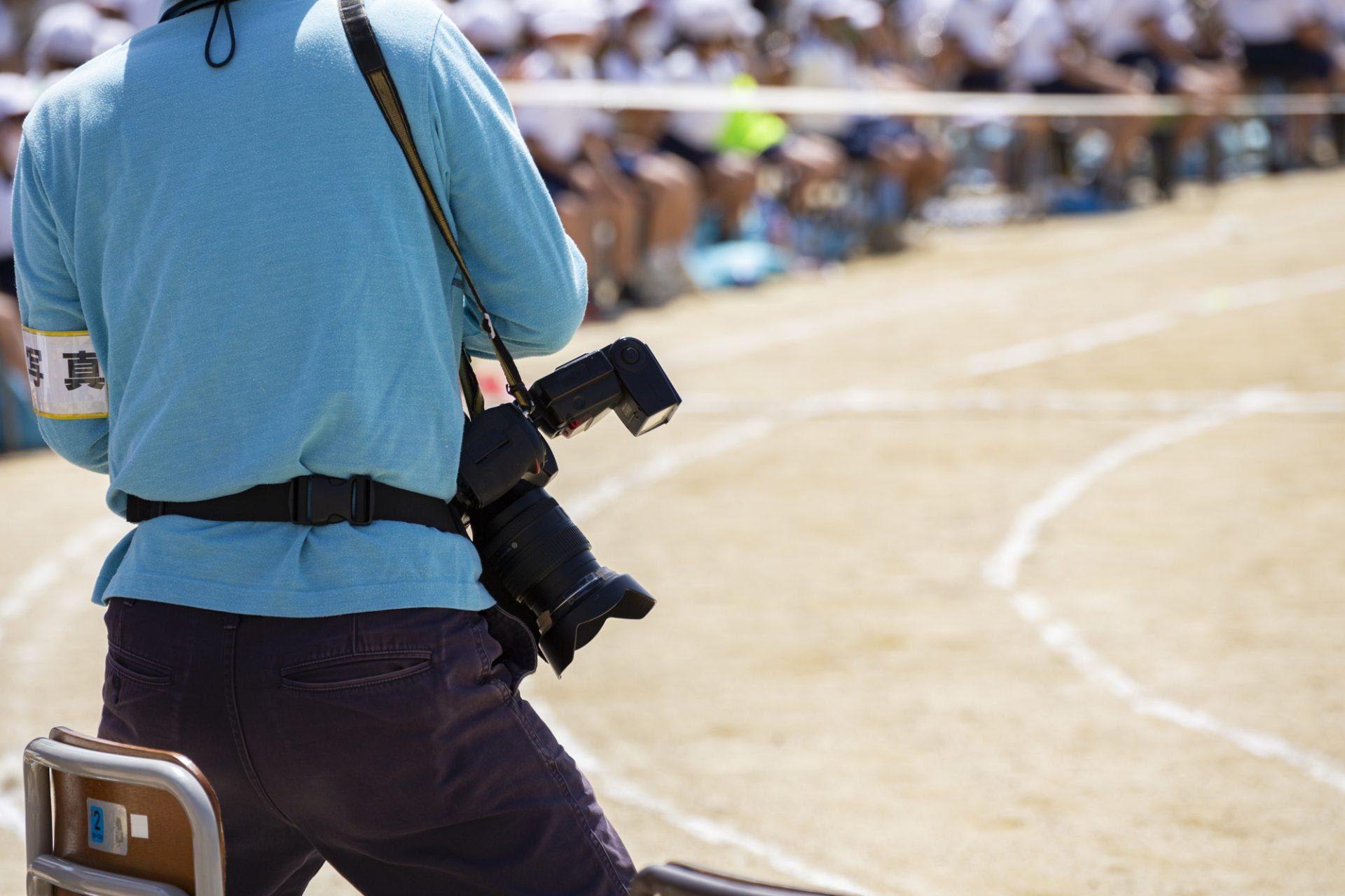 運動会を撮影するカメラマン